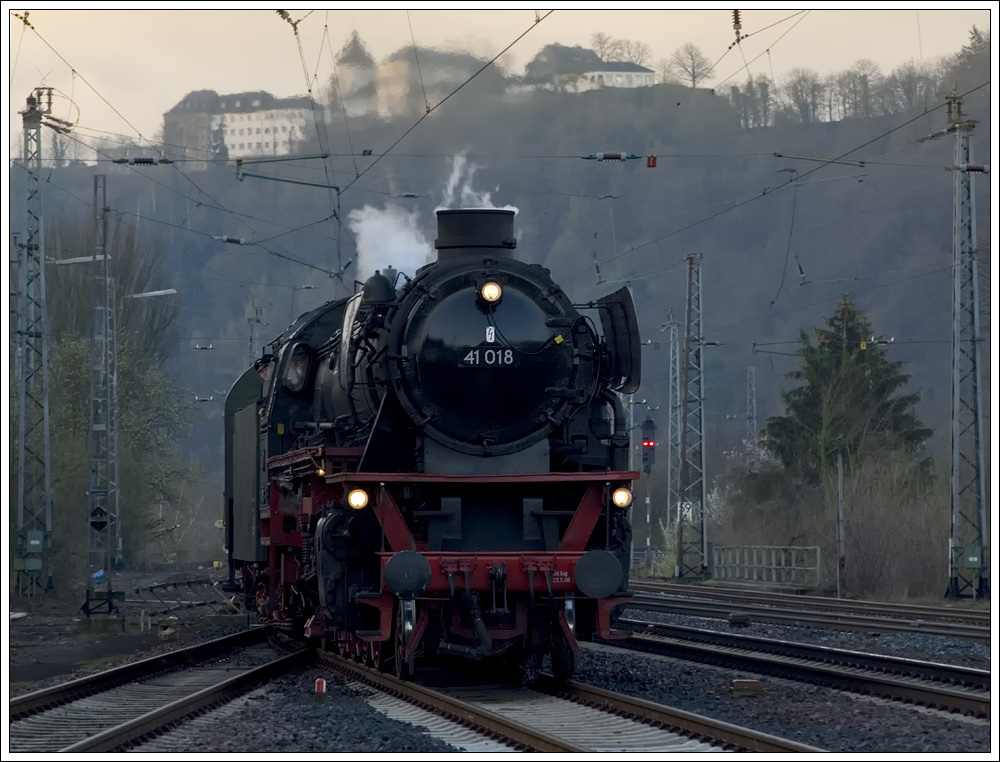Zwei Minuten vor Plan erreichte 41 018 mit ihrem Sonderzug 39130 aus Trier am 5.4.2010 den mit einem Architekturpreis des Landes Rheinland-Pfalz ausgezeichnete Umweltbahnhof Bullay. Im Hintergrund ist die Pndericher Marienburg zu sehen.