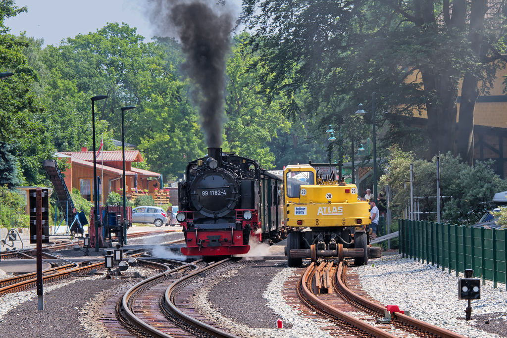 Zweiwegebagger auf Schmalspur abgestellt und Ausfahrt des Rasenden Rolands in Ghren. - 09.07.2013 - Aufgenommen vom Bahnsteig (ohne Bezeichnung) am R.