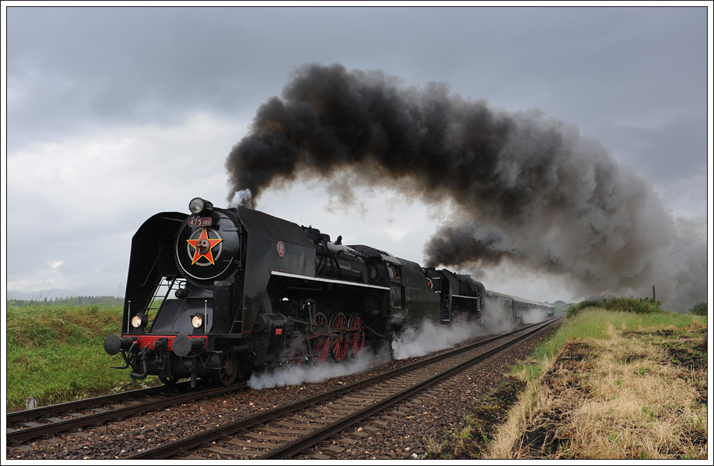 Zwischen 1. und 3. Juni fanden in Vr�tky die Kindertage 2012 statt. Aus diesem Anlass wurden von und nach Vr�tky zahlreiche Sonderz�ge in Verkehr gesetzt. Den Anfang machten am 1.6.2012 475 196 und 475 179 mit ihrem Sonderzug Os 31207 von Vr�tky �ber Zvolen retour nach Vr�tky. Die Aufnahme zeigt den Zug bei der vor Horn� �tubňa. Zurecht bekam die BR 475 wegen ihres eleganten �u�eren erhielten die Lokomotiven vom Betriebsdienst den Spitznamen „�lechtična“ (Edelfrau). 