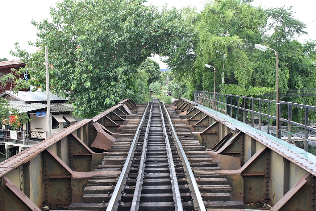 Zwischen den 2 Bahnsteigen der Hst. Chom Thong berquert diese Eisenbahn- und Fugngerbrcke einen Khlong (Kanal); Blickrichtung Wongwian Yai am 24.Juli 2012.

