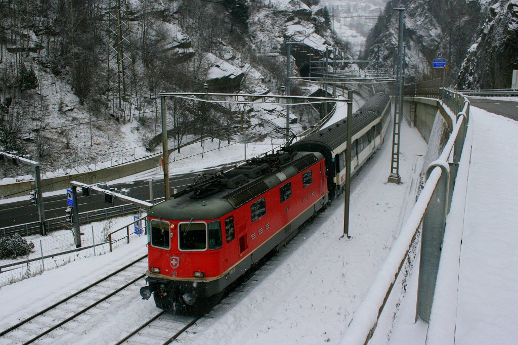 Zwischen Autobahn und Kantonsstrasse zieht die Re 4/4 II 11193 am 28.11.2010 den IR 2174 (Locarno - Basel SBB) bergwrts. Die Aufnahme entstand bei Rodi-Fiesso, im Hintergrund ist der schmale Einschnitt der Piottino-Schlucht zu erkennen, die sowohl Bahn als auch beide Strassen mittels Tunnels umfahren. 