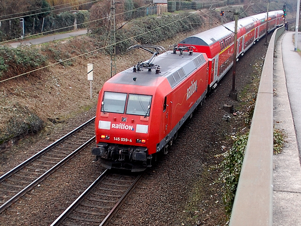 Zwischen Rheydt Hbf und Mnchengladbach Hbf donnert 145 039-4 mit einem RE4 an der Strae Hangbuschweg vorbei. 10.2.2011