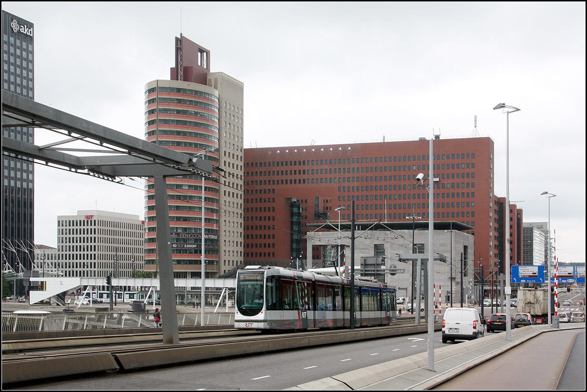 . Auffahrt zur Erasmusbrücke -

Mit dem Neubau der Erasmusbrücke in Rotterdam wurde 1996 die Straßenbahn südlich der Nieuwe Maas wieder mit dem Netz nördlich des Stromes verbunden. 

Ein Teil der Erasmusbrücke kann für Schiffe hochgeklappt werden. Dafür ist die aufwändige Oberleitungskonstruktion nötig, da sich hier der Drehpunkt der Klappbrücke befindet und somit auch die Oberleitung mit nach oben geklappt werden muss.

21.06.2016 (M)