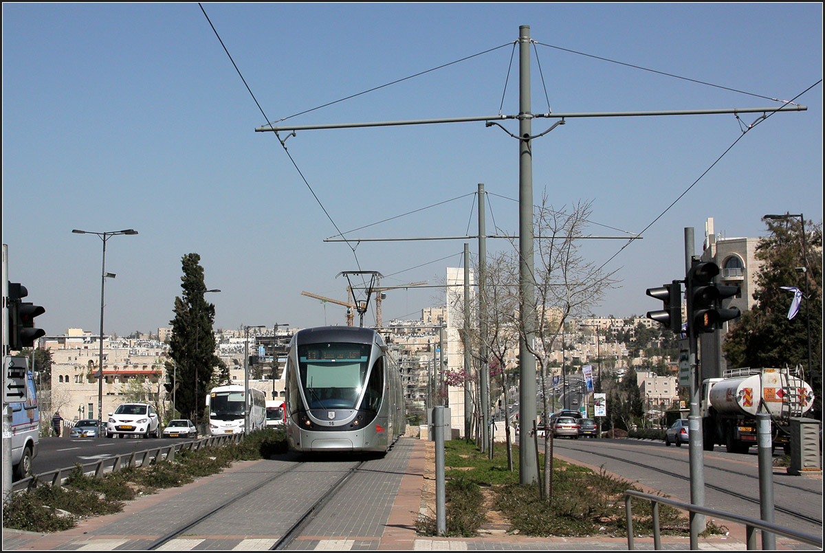 . Entlang der Green Line - 

Zwischen der Haltestelle Shim'on Ha-Tsadik bis kurz vor der Station City Hall folgt die Trassenführung der neuen Stadtbahn in Jerusalem in etwas der ehemaligen Waffenstillstandslinie von 1949. Von 1949 bis 1967 war Jerusalem eine geteilte Stadt. 1967 im Sechs-Tage-Krieg wurde Ostjerusalem von Israel erobert und annektiert. Nördlich der Station Shim'on Ha-Tsadik verkehrt die Bahn durch Ostjerusalem, um im Norden der Stadt eine große jüdische Siedlung anzuschließen. Nach passieren der Old City wird das westliche Jerusalem durchfahren.

Im Bild fährt eine aus Norden kommende Citadis-Tram in die Haltestelle Shivtei Israel ein.

20.03.2014 (M)
