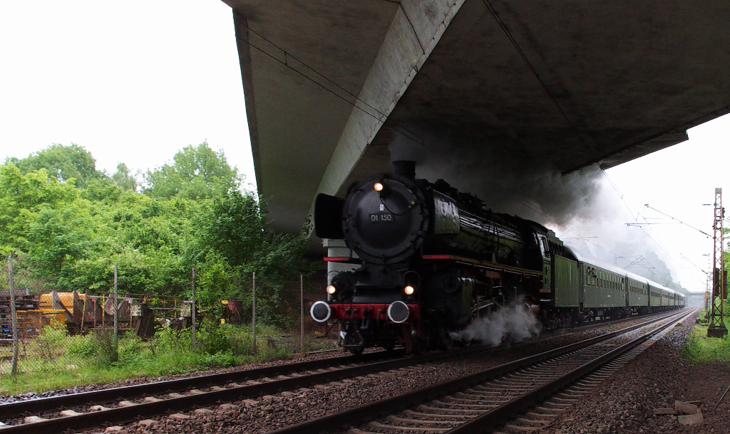 01 150 im Saarland unterwegs - Richtiges Sauwetter herrschte am 10.05.2014 im Saarland.
Leider haben die Dampfloksonderfahrten ins Saarland in der letzten Zeit kein Wetterglück.
01 150 ist mit ihrem Sonderzug auf der Rückfahrt von Saarbrücken nach Gerolstein.
Bei Dauerregen macht das Warten nicht richtig Spaß, wenigstens hatten wir unter der Brücke der B51 in Dillingen einen trockenen Platz.

In der Nähe ist das Tierheim und viele junge Leute gehen mit den Hunden spazieren und zeigten sich überrascht über das Schwarze Ungetüm, denn sie hatten vorher noch nie eine Dampflok in Aktion gesehen.

Bahnstrecke 3230 Saarbrücken - Karthaus