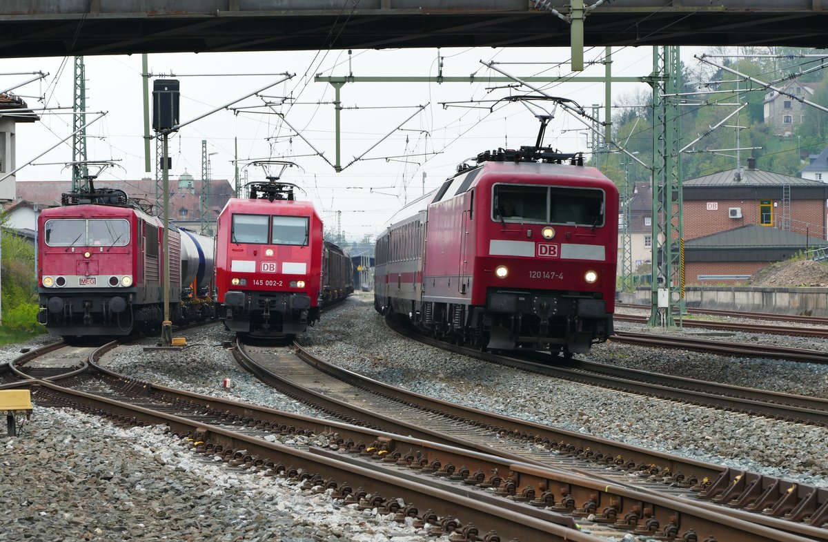 04.05.2017, Hochbetrieb in Kronach. Links  warteten die MEG Loks 705 (ex DR 250 196), und 609 (ex DR 143 175) schon eine Weile mit einem Ganzzug aus Staubgutwagen des Schweizer Einstellers WASCOSA. In die Mitte hatte sich 145 002 mit einem gemischter Güterzug gestellt. Der durfte nach der Durchfahrt des IC 2300 seine Fahrt in Richtung Saalfeld zuerst fortsetzen. Die Aufnahme unter der Nordbrücke stellt auf der oft sehr schwach frequentierten Strecke eine Ausnahme dar.