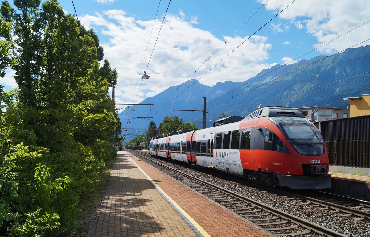05.07.2020, Rum bei Innsbruck: Der ehemalige Vorarlberger Talent 4024 033-5 ist als REX 5224 auf dem Weg von Kufstein nach Brennero/Brenner in der Haltestelle zum Stehen gekommen und wartet nun vor dem beeindruckenden Panorama der Nordkette seine planmäßige Minute Aufenthalt ab, bevor es pünktlich um 16:35 in der Nachmittagshitze weiter zum Innsbrucker Hauptbahnhof geht.
Ein noch so junges Bild und doch schon gänzlich historisch, denn der Talent wurde inzwischen ins Cityjet-Design umgestaltet und die Haltestelle ist leider nicht mehr so grün bewachsen und hat ihren Charme weitestgehend verloren, weil eine neue Mobilitätsdrehscheibe errichtet wird.... 