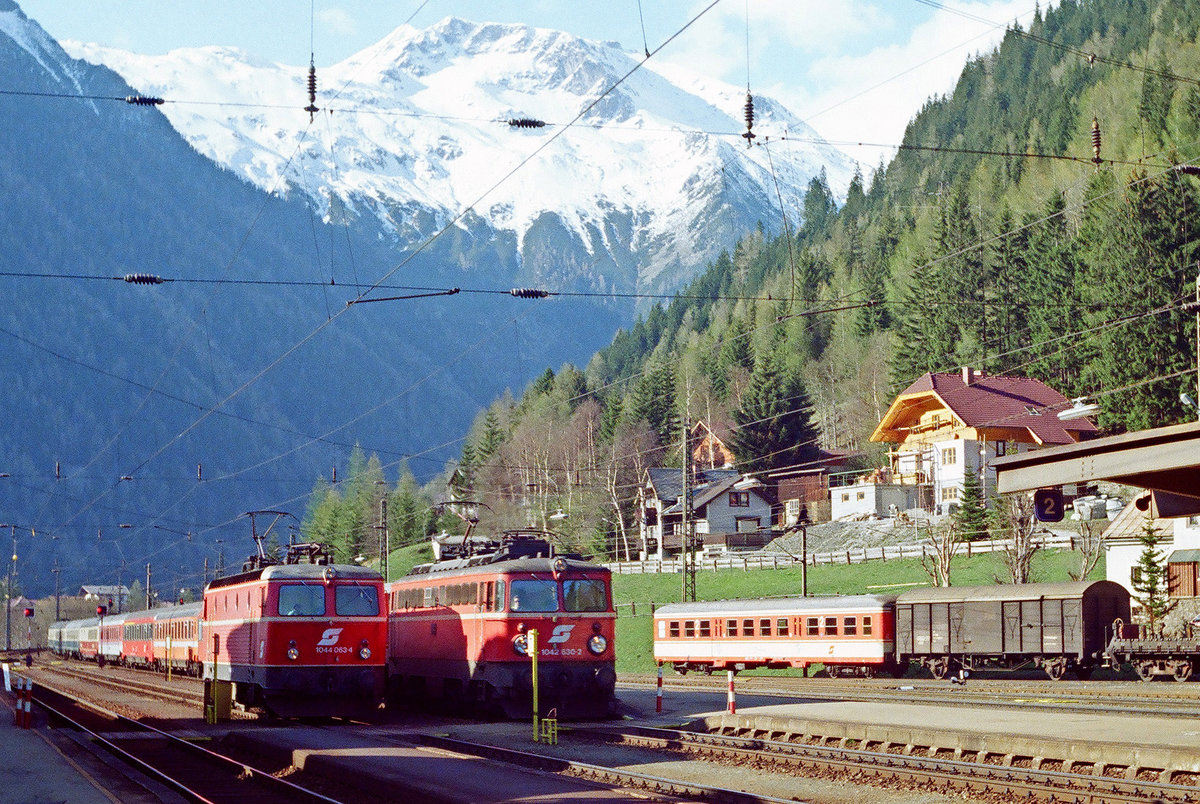 05.Mai 1990: Im Bahnhof Mallnitz warteten wir auf „unseren“ Zug durch die Tauernschleuse. Lok ÖBB 1044 063 mit einem Zug nach Süden und ÖBB 1042 630 stehen im Bahnhof.
