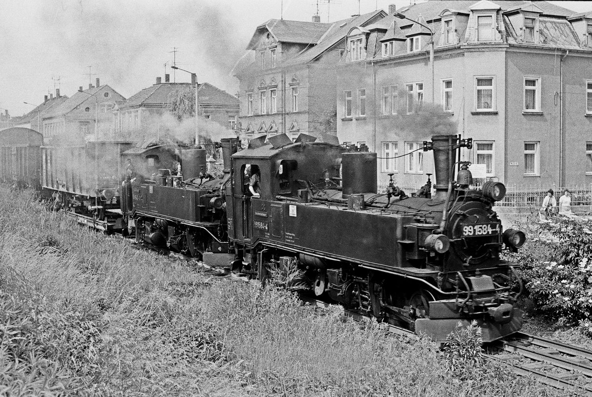 10.06.1982, Oschatz, Schmalspurbahn, Lokomotiven 99 1584 und 99 1542 mit einem Zug Regelspurwagen auf 750 mm-Rollwagen nach Mügeln.