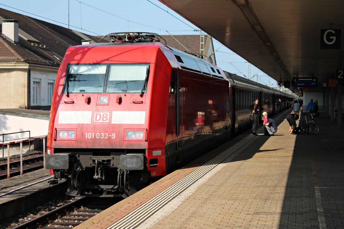 101 033-9 stand am 04.10.2014 kurz nach der Ankunft mit dem EC 7 (Hamburg Altona - Zürich HB/Chur HB) in Basel Bad Bf auf Gleis 2. Wegen Bauarbeiten auf Schweizer Seite kuppelt, wie auf dem Bild zusehen, die 101 033-9 schon im Badischen Bahnhof vom Wagenpark ab und die Re 460 045-8  Rigi  übernimmt den Zug bis Zürich HB.