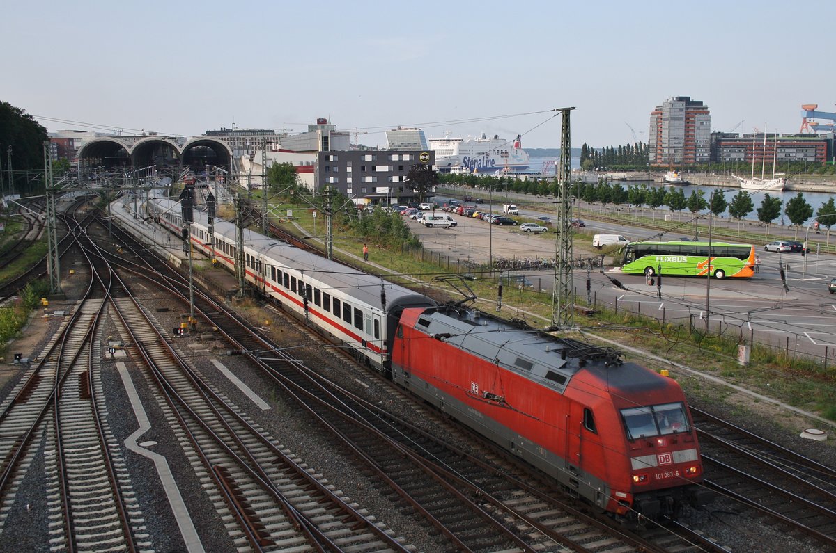 101 063-6 verlässt am Abend des 24.7.2016 mit dem IC2225 von Kiel Hauptbahnhof nach Köln Hauptbahnhof die Stadt an der Förde. Im Hintergrund läuft das Fährschiff Stena Scandinavica nach Göteborg aus.