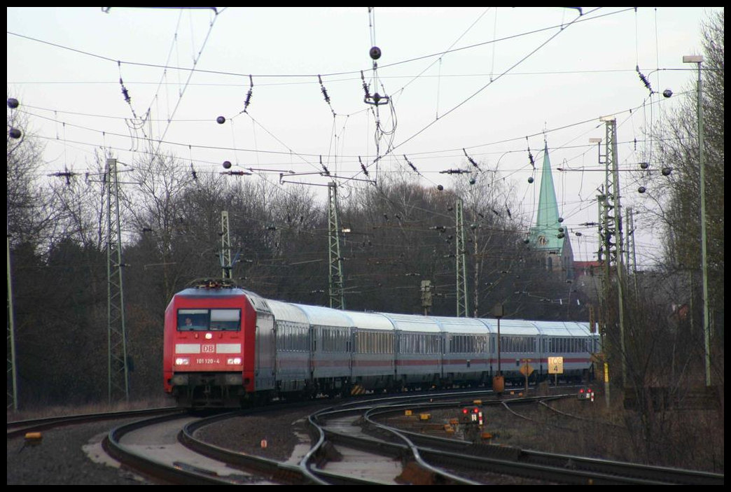 101120 hat hier gerade am 20.3.2005 den Bahnhof Hasbergen durchfahren und ist mit ihrem Intercity auf dem Weg zum nächsten Halt in Münster in Westfalen. Im Hintergrund ist die Spitze der evangelischen Kirche von Hasbergen zu sehen.