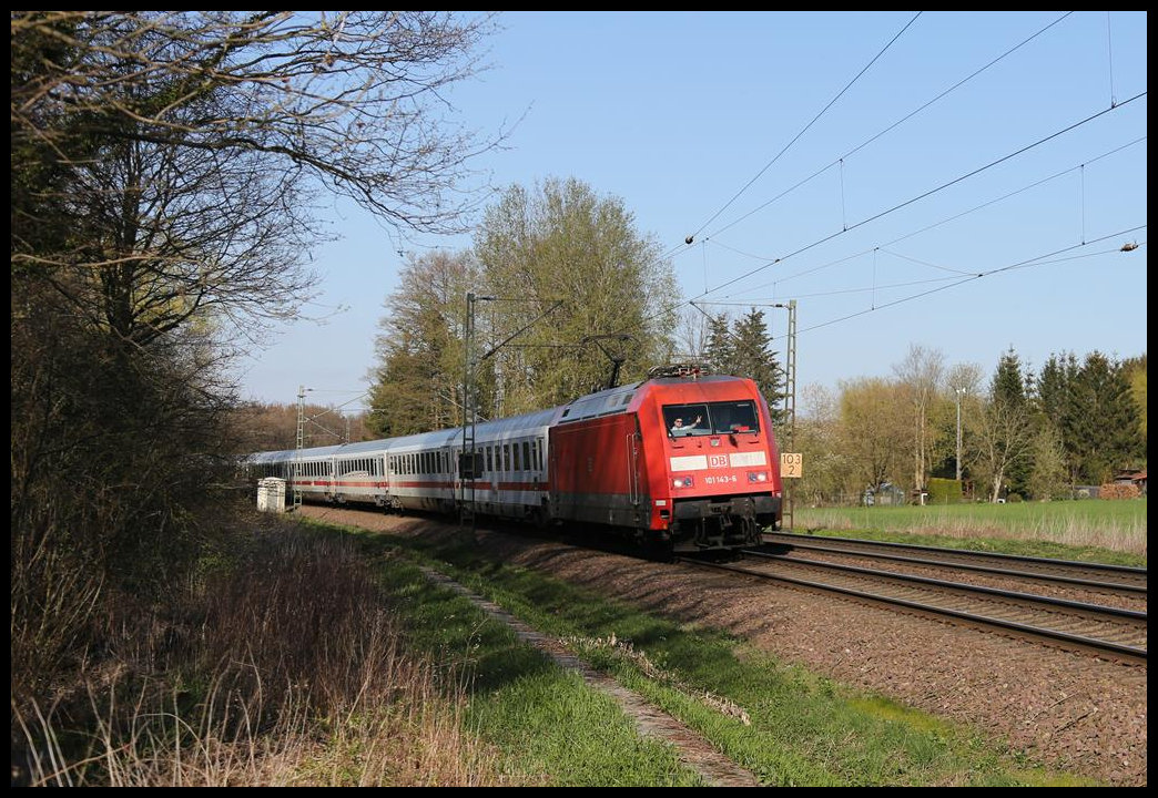 101143-6 hat hier am 10.4.2019 um 17.22 Uhr mit einem grüßenden Lokführer gerade Niedersachsen verlassen und fährt nun bei Tecklenburg in Nordrhein Westfalen auf der Rollbahn in Richtung Münster weiter.