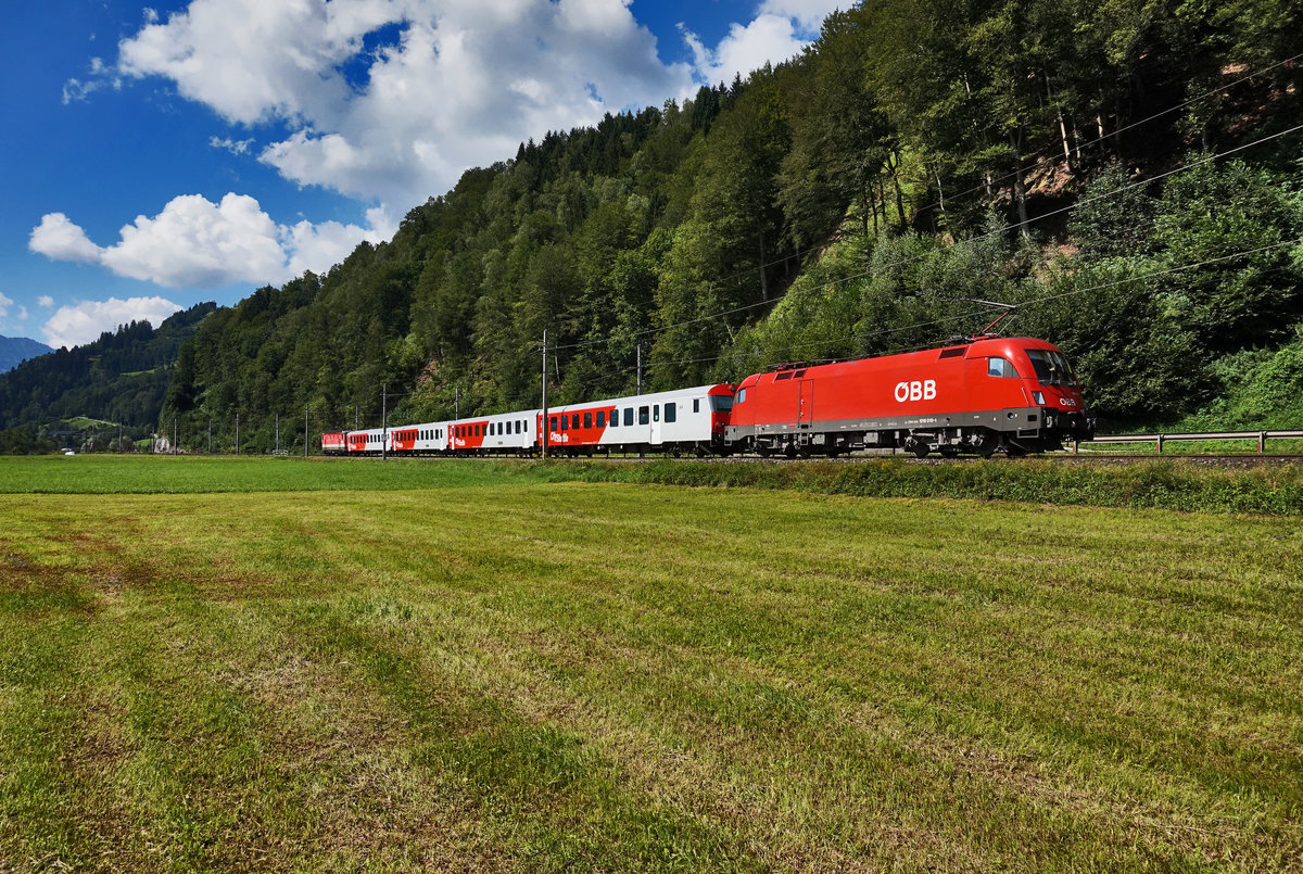 1016 018-4 und 1144 225-0 am Zugschluss, sind mit einem nicht im Fahrplan vermerkten Zug von Schwarzach-St. Veit nach Salzburg Hbf, nahe Mitterberghütten unterwegs. Insgesamt war diese Garnitur an dem Tag zwei mal unterwegs.
Aufgenommen am 7.8.2016.