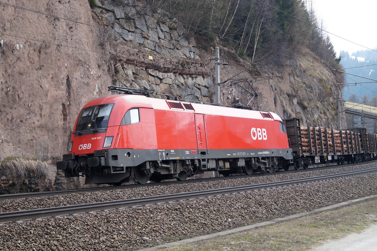 1016 037-4 legt sich bei Gries am Brenner mit einem Holzzug am Haken in die Kurve und fährt talwärts Richtung Innsbruck, 13.04.2019.