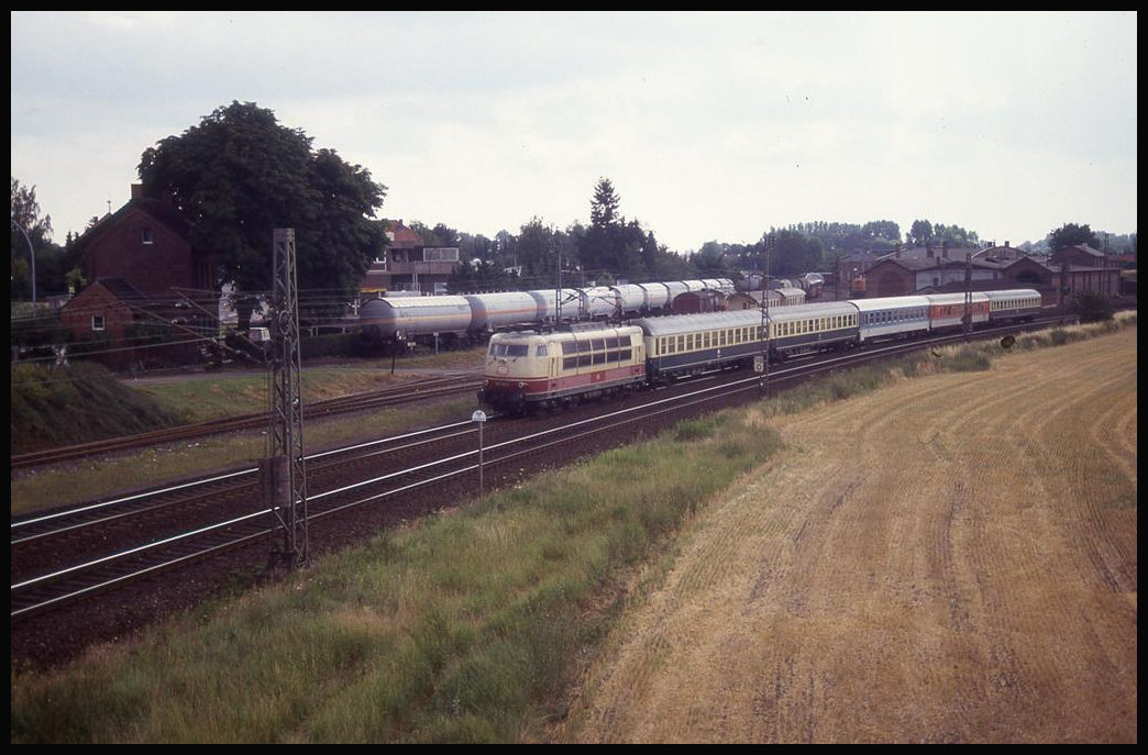 103120 fährt hier am 10.7.1993 mit einer bunten Wagengarnitur Richtung Osnabrück am Bahnbetriebswerk der Teutoburger Wald Eisenbahn vorbei.