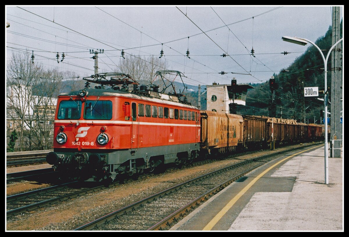 1042 019 fährt am 19.03.2004 mit einem Güterzug durch den Bahnhof Bruck an der Mur. Das Stellwerk im Hintergrund war damals noch in Betrieb.