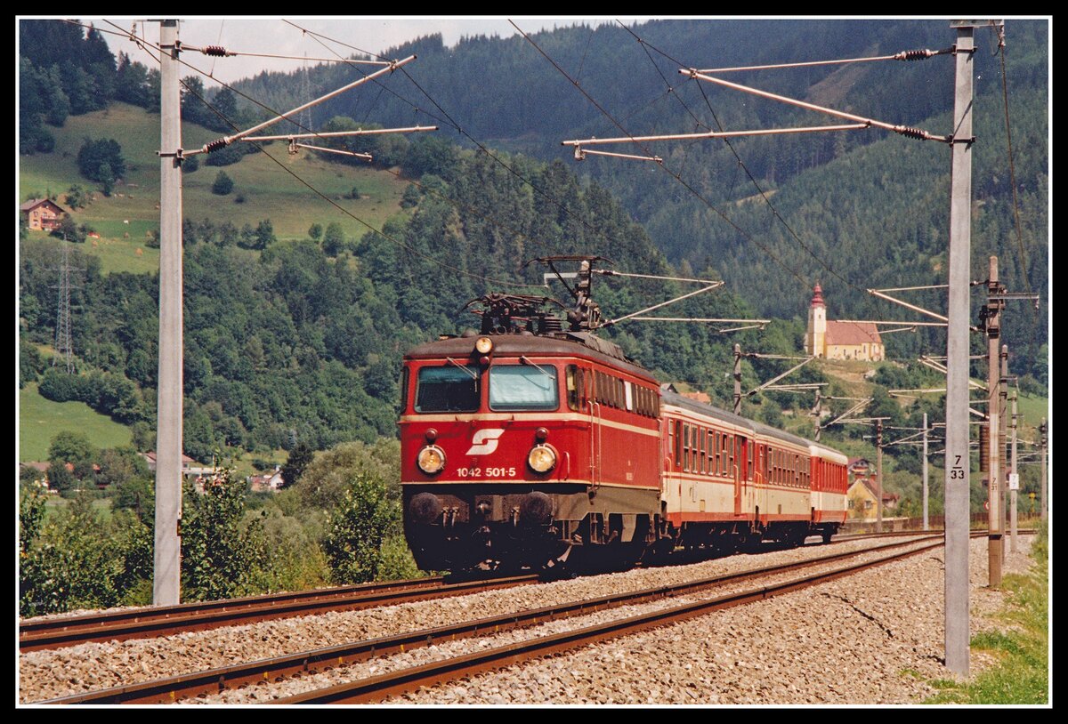 1042 501 mit Eilzug bei Oberaicham 9.08.1994. im Hintergrund ist die Kirche von St.Dynoisen zu erkennen.