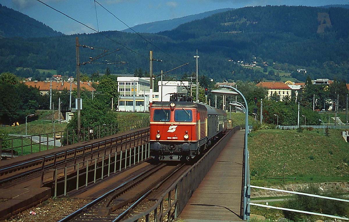 1044 007-4 überquert Ende der 1990er Jahre mit einem Regionalzug Richtung Arnoldstein die alte Draubrücke in Villach. Heute verhindern leider die Schallschutzwände des Neubaus eine solche Aufnahme.