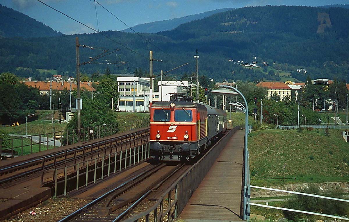 1044 007-4 überquert Ende der 1990er Jahre mit einem Regionalzug Richtung Arnoldstein die alte Draubrücke in Villach. Heute verhindern leider die Schallschutzwände des Neubaus eine solche Aufnahme.