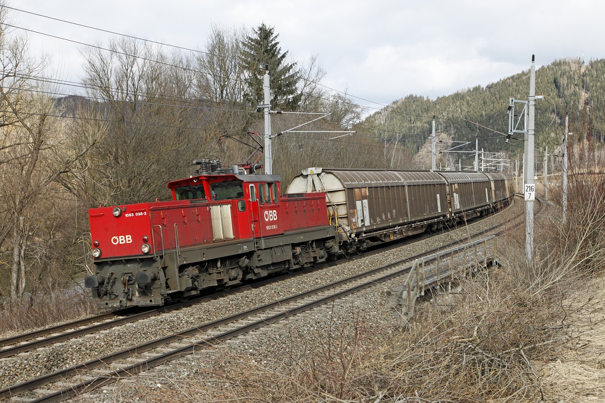 1063 038 mit Güterzug zwischen Kraubath und Fentsch St.Lorenzen am 24.02.2016. Die Kilometertafel mit 216,7 stammt noch von der Kilometrierung der Kronprinz-Rudolfbahn die von St.Valentin über Hieflau, Schoberpaß, Feldkirchen in Kärnten noch Tarvis führte.