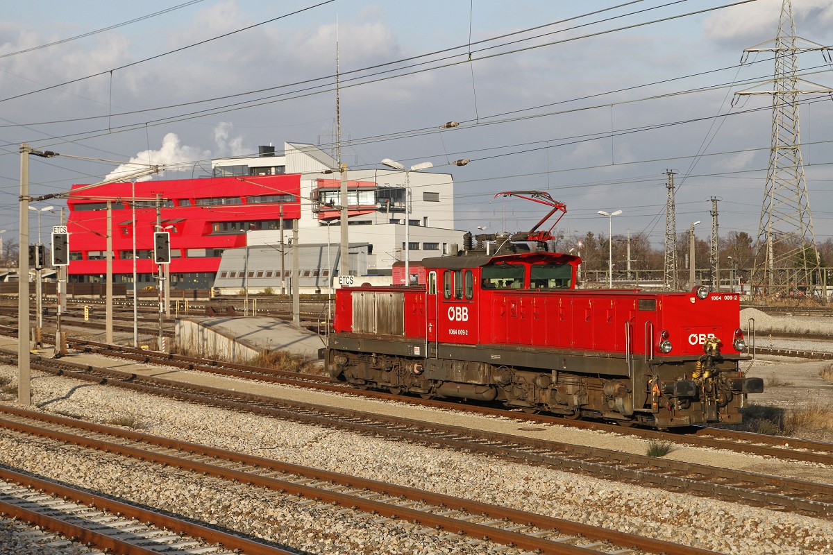 1064 009 in Wien Zentralverschiebebahnhof am 10.12.2015. Im Hintergrund ist ein Betriebgebäude des Bahnhofs zu erkennen.