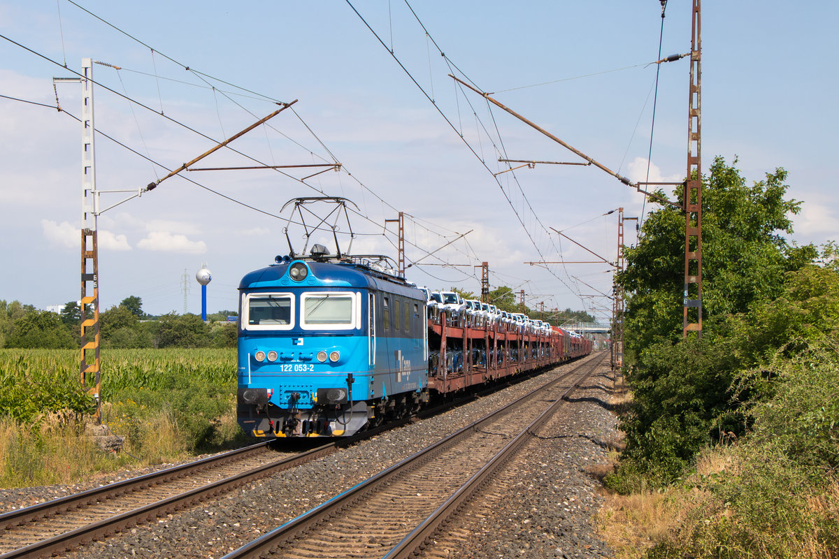 11. Juli 2019 in Velké Zbozí: 122 053-2 kommt mit einer langen Leine Autos gerade aus Nymburk angefahren gen Süden oder Osten. 