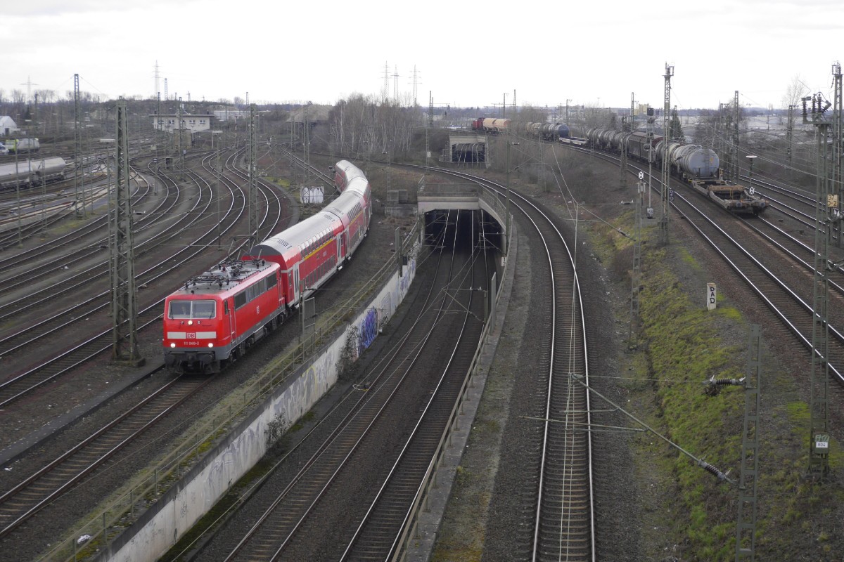 111 040-3 fährt mit ihrem RE 4 nach Aachen durch das Modellbahn-Diorama der nördlchen Ein-/Ausfahrt des Neusser Hauptbahnhofs. Rechts zieht eine Chemion-MaK einen Behälterzug von Dormagen ins benachbarte Werk Uerdingen, ganz links am Rand steht Captrain 185 550 (Aufnahme vom 12.2.16)