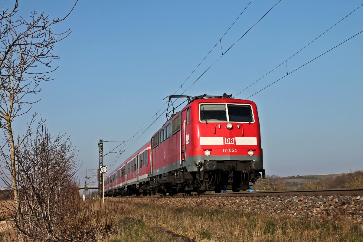 111 054 am 08.03.2014 wieder auf dem Weg von Freiburg (Brsg) Hbf nach Neuenburg (Baden), als sie kurz vor ihrem vorletzten Zwischenstop in Müllheim (Baden) am Örtchen Hügelheim vorbei kommt.