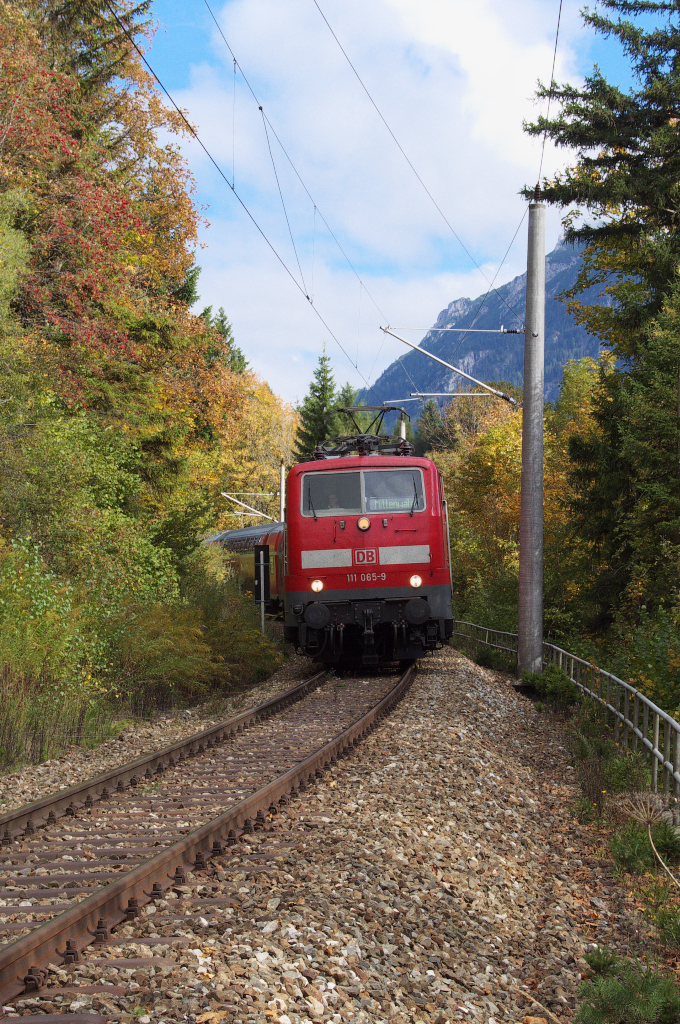 111 065-9 hat es fast bis zum Zielbahnhof Mittenwald geschafft.
Es geht nur noch bergab, nachdem die Regionalbahn Mnchen Hbf.- Mittenwald den Schmalensee umrundet hat.
Nach der berquerung der Staatsstrae 2542 mit Hilfe einer Stahltrgerbrcke rollt der Zug hinab ins Tal der Isar.
Die Schmalenseehhe liegt auf 960 Metern Hhe, der Zielbahnhof Mittenwald auf 914 Meter.
Ein schmaler Steg mit Gleisberquerung bringt den Wanderer ebenfalls ins Tal.
Die Zge hrt man aber schon von sehr weit kommen, denn die vielen unbeschrankten B mit Pfeiftafeln und den damit verbundenen schrillen Pfiffen machen auch den Fotografen auf das Herannahen eines Zuges aufmerksam.
07.10.2013 - Bahnstrecke 5504 Mnchen Hbf. - Mittenwald Grenze.
