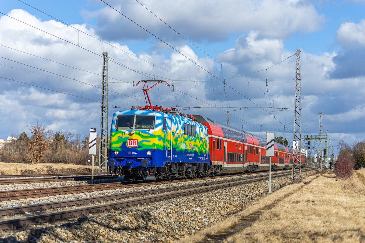 111 074  Hilde  mit einem Dosto Zug auf dem Weg nach Garmisch Partenkirchen zwischen München Locham und München Westkreuz am 26.02.2022