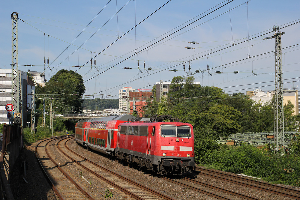 111 105 bespannte am 6. August 2015 den RE 7 von Krefeld nach Münster (Westfalen).
Mittlerweile sind hier Talent 2-Triebzüge des Unternehmens National Express im Einsatz.
Die Aufnahme entstand östlich des Wuppertaler Hauptbahnhofs.