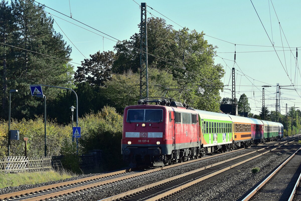 111 137 rauscht mit ihrem Hetzerather bestehend aus einem bunten Mix von Reisezugwagen durch Angermund gen Duisburg. 

Angermund 09.10.2022