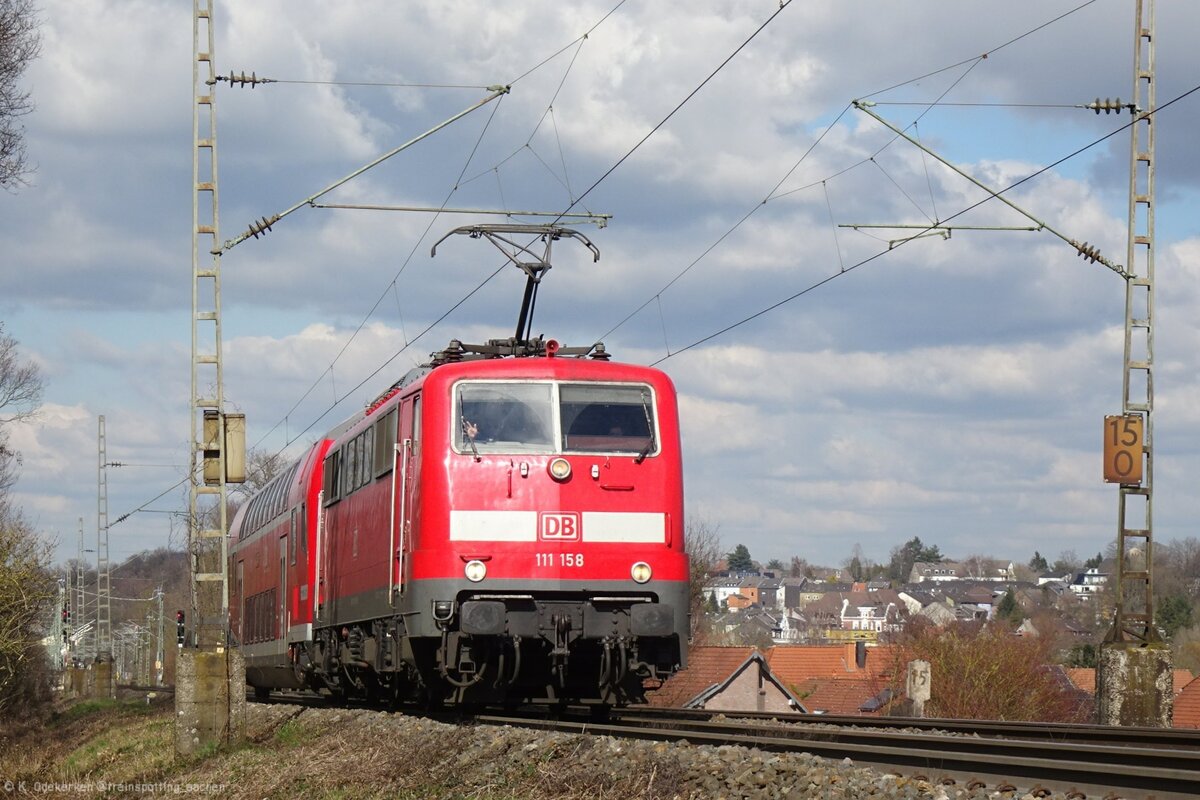 111 158 bringt einen Doppelstocksteuerwagen für den RE9 nach Aachen und saust durch Herzogenrath. 