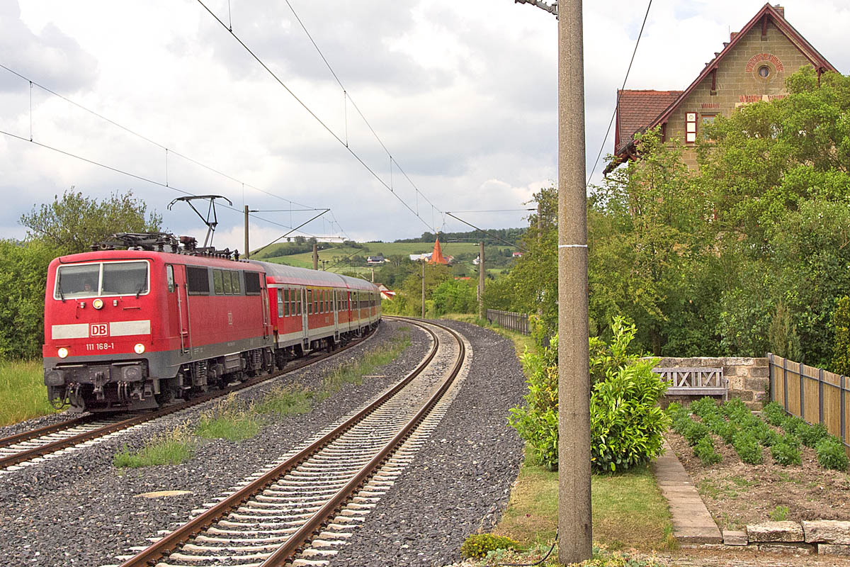 111 168 fuhr mit einem Eilzug nach Stuttgart durch Ellrichshausen. Von dem Bahnsteig, der bis 1985 zwischen den beiden Gleisen lag, war am 7.7.13 nichts mehr zu sehen. 