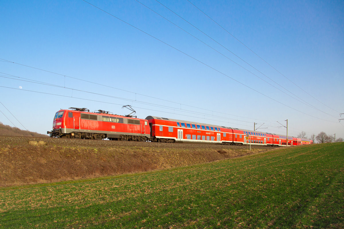 111 217-6 zieht ihren Doppelstockwagen zwischen Neustadt Aisch und Diebach in Richtung Würzburg. Aufgenommen am 25.02.2021. 