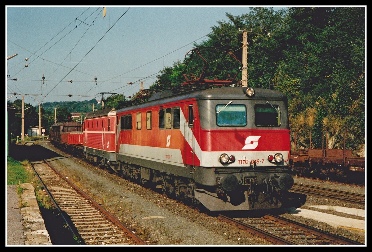 1110 018 + 1044 082 ziehen am 22.August.2000 einen Güterzug durch den Bahnhof von Velden am Wörthersee.