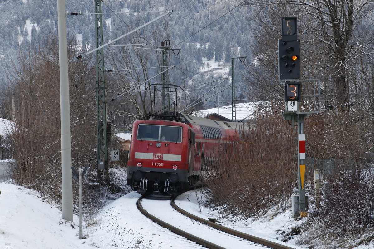 111058 mit Doppelstockwagen aus Mittenwald kommend am 19.01.2020 vor der Einfahrt zum Bahnhof Garmisch-Partenkirchen. Der firsch gefallene Schnee brachte keine Verzögerungen im Bahnbetrieb und bietet einen schönen Kontrast zum bahnrot.