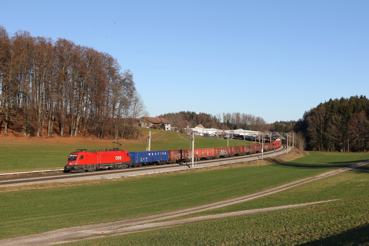 1116 094 war am 18. Dezember 2023 mit einem gemischten Güterzug bei Axdorf im Chiemgau in Richtung München unterwegs.