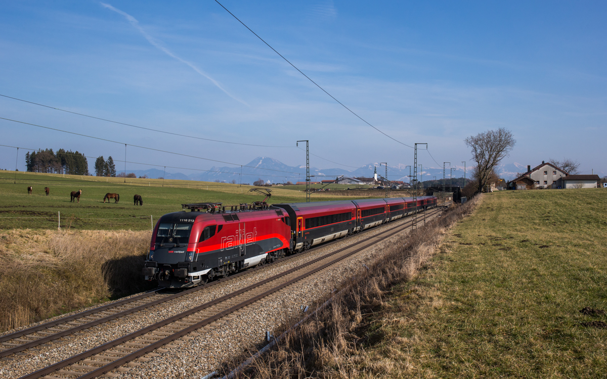 1116 213 fährt mit einem Railjet bei Teisendorf in Richtung Rosenheim, aufgenommen am 24. März 2018.