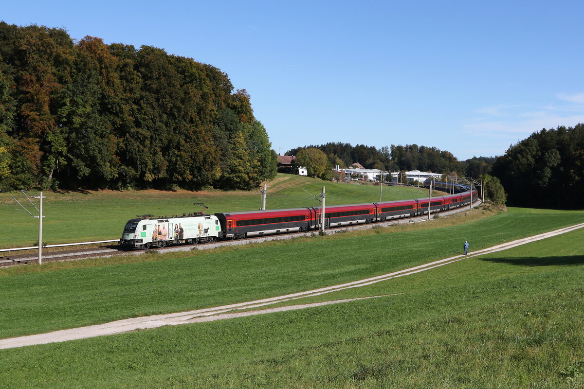 1116 231  BIO AUSTRIA II  mit einem  Railjet  am 21. Oktober 2023 bei Axdorf im Chiemgau.
