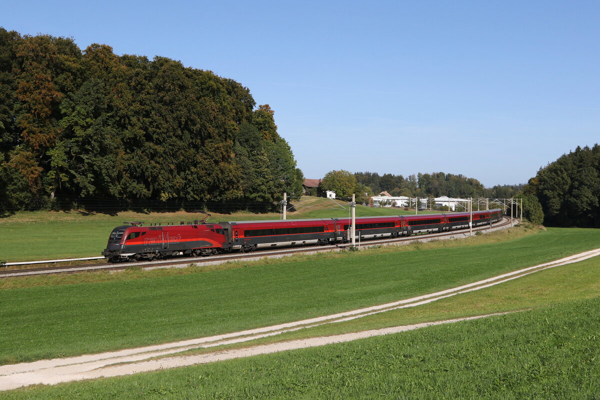 1116 239 mit einem  Railjet  aus Salzburg kommend am 11. Oktober 2023 bei Axdorf im Chiemgau.