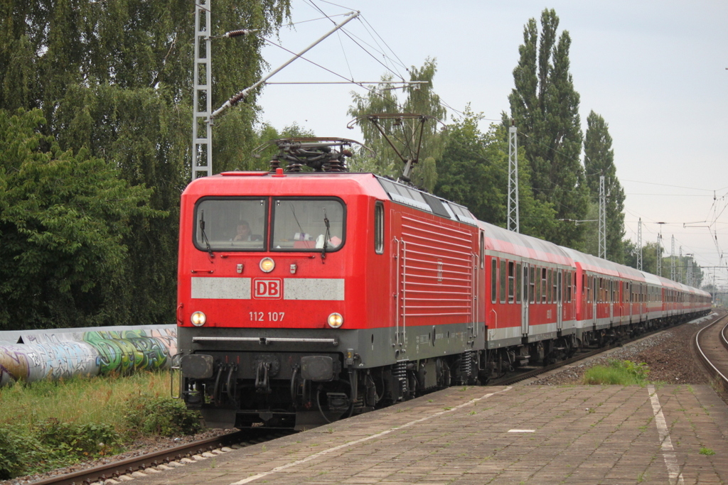 112 107-8 mit dem Pommes Rot-Wei Express 13290 von Warnemnde nach Berlin-Ostbahnhof bei der Durchfahrt am 12.08.2015 im Haltepunkt Rostock-Holbeinplatz,inklusive 2xSteuerwagen hinter der Lok und am Ende lief noch ein 3.Steuerwagen mit.