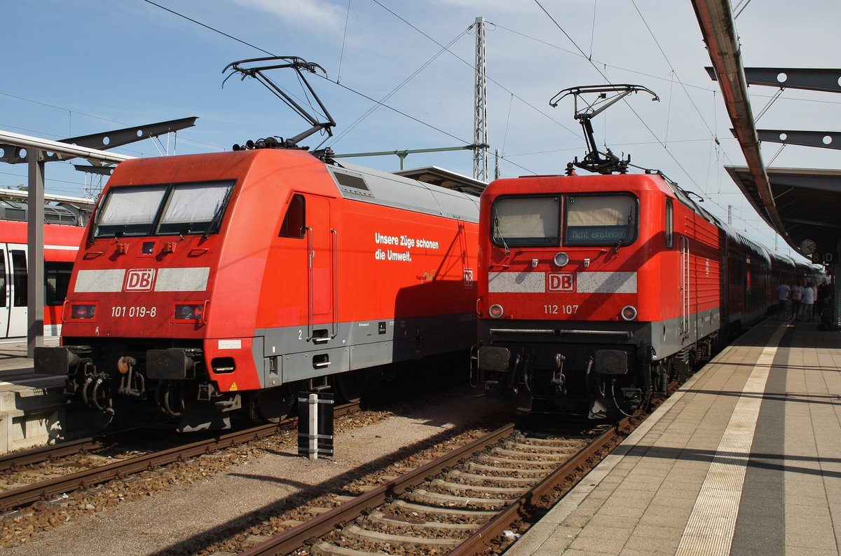 112 107 hat noch etwas Zeit bis zu ihrer Abfahrt mit dem RE5 (RE4365) von Rostock Hauptbahnhof nach Elsterwerda auf dem Nebengleis drückt währenddessen 101 019-8 den IC2086 von Hannover Hauptbahnhof nach Stralsund Hauptbahnhof mit +35 aus dem Rostocker Hauptbahnhof. (22.7.2016)