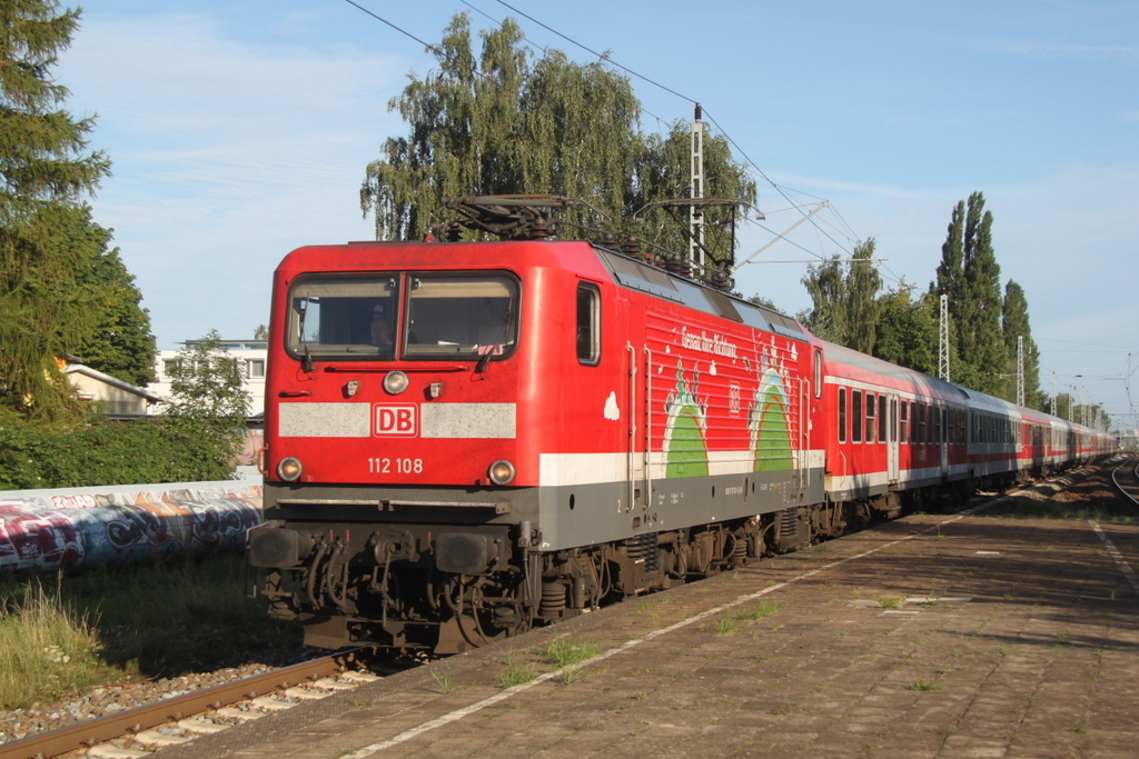 112 108-6( Genau Ihre Richtung ) mit dem Pommes Rot-Wei Express 13290 von Warnemnde nach Berlin-Ostbahnhof bei der Durchfahrt am 29.08.2015 im Haltepunkt Rostock-Holbeinplatz 