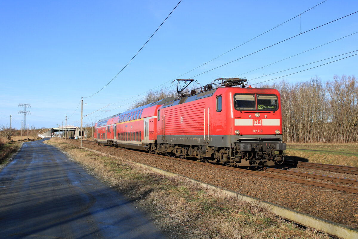 112 113 zog am 22.01.2022 den RE7 von Stralsund Hbf nach Greifswald. Aufgenommen bei Brandshagen.