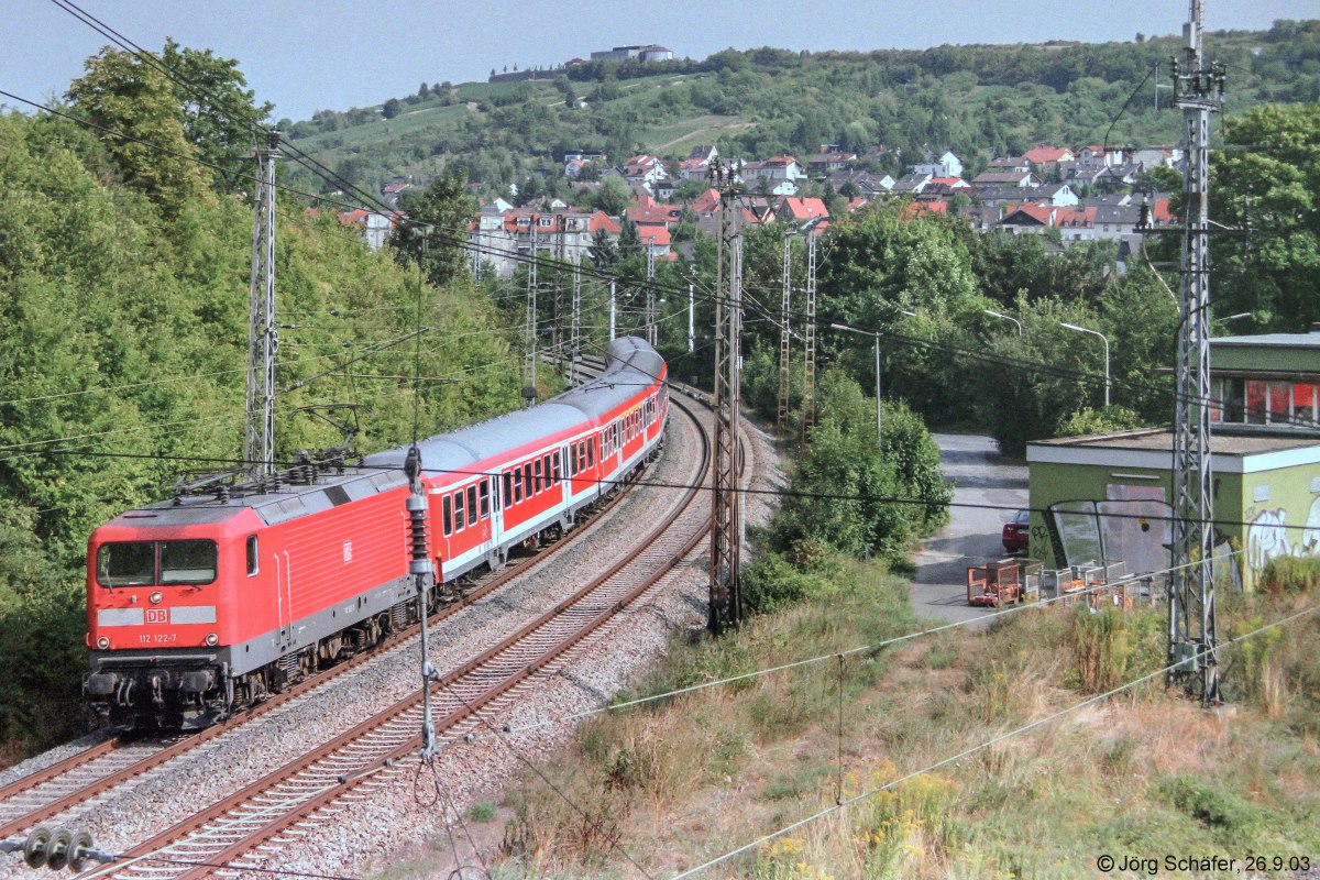 112 122 fuhr mit ihrem 4-Wagen-Zug nach Würzburg Hbf am 26.9.03 am Bahnhof Heidingsfeld West vorbei, dessen Stellwerk man am rechten Bildrand sieht.