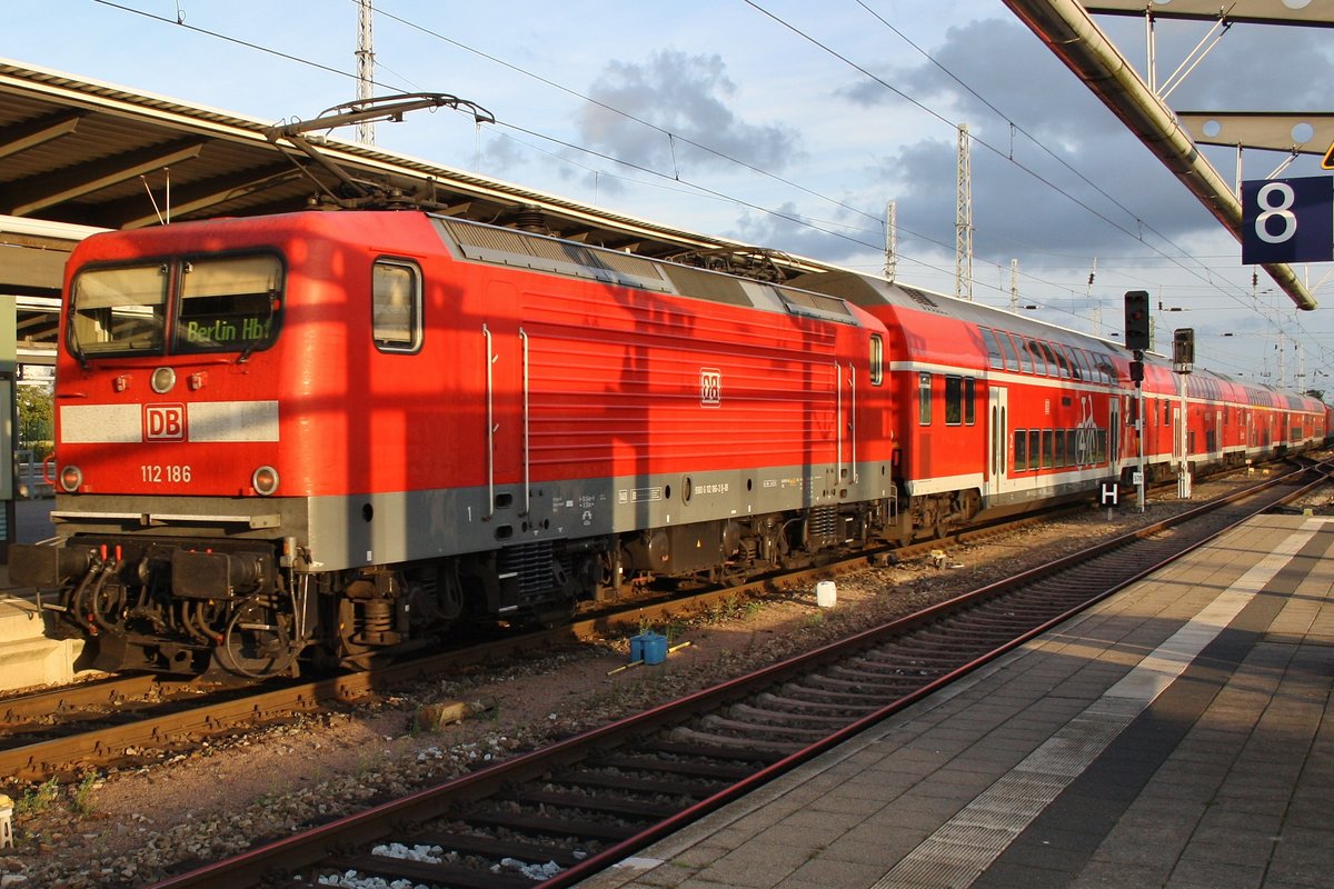 112 186 drückt den RE18491  Warnemünde-Express  von Warnemünde nach Berlin Hauptbahnhof (tief) am 17.9.2016 aus dem Rostocker Hauptbahnhof. An der Zugspitze führte 112 107.
