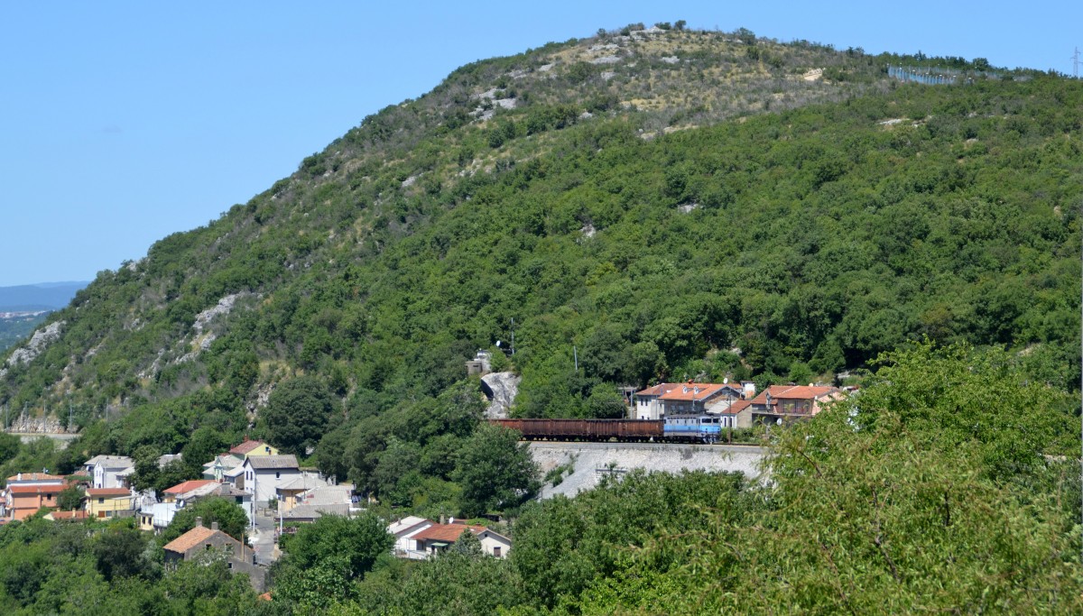 1141 019 schraubt sich mit einer Reihe Eoas als Tv 61005 Rijeka - Zagreb Ranžirni kolodvor am 10.07.2015 die Rijekarampe hoch. Hier passiert sie gerade die Ortschaft Draga