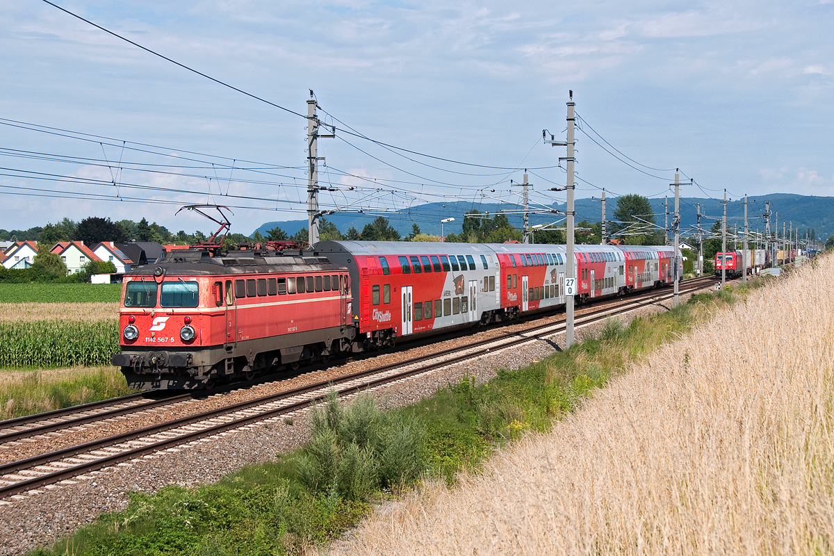 1142 567 ist mit dem REX 2173 nach Wien FJB unterwegs. Die Aufnahme entstand am 22.07.2017 kurz vor Muckendorf-Wipfing.